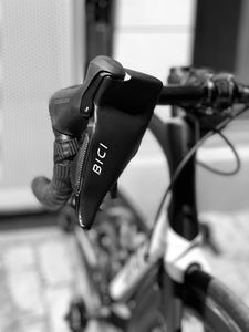 Bici Shield installed on the brake lever of a roadbike's handlebars showing white bici logo and black hand protector