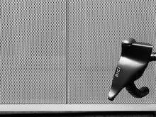 Load image into Gallery viewer, Another closeup of the winter riding Shield by Bici, with a fine mesh grate in the background.